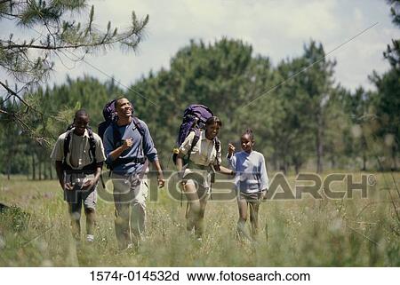 Stock Image - Parents hiking with their son and daughter in a field. Fotosearch