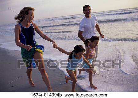 Parents running with their two children on the beach View Large Photo Image Stock Image - Parents running with their two children on the beach. Fotosearch