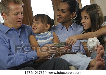 Parents sitting with their two daughters holding money View Large Photo Image Picture - Parents sitting with their two daughters holding money. Fotosearch