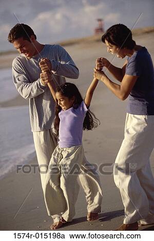 Parents swinging their daughter on the beach View Large Photo Image Stock Image - Parents swinging their daughter on the beach. Fotosearch