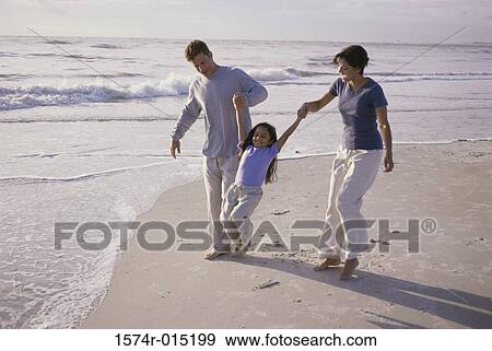 Parents swinging their daughter on the beach View Large Photo Image Stock Photo - Parents swinging their daughter on the beach. Fotosearch