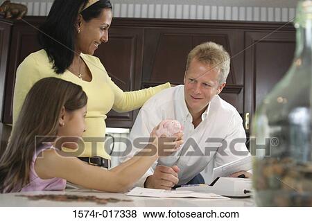 Stock Photo - Parents with their daughter holding a piggy bank. Fotosearch