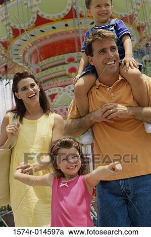 Stock Image - Parents with their son and daughter in an amusement park. Fotosearch