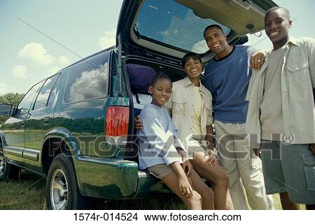 Picture - Parents with their son and daughter behind a car. Fotosearch