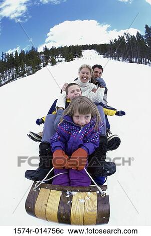 Parents with their son and daughter sliding down a hill on a toboggan View Large Photo Image Stock Image - Parents with their son and daughter sliding down a hill on a toboggan. Fotosearch