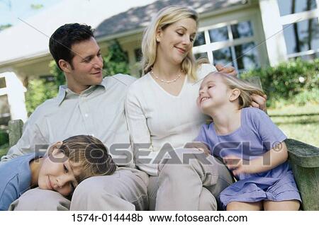 Stock Image - Parents with their two children sitting on a bench. Fotosearch