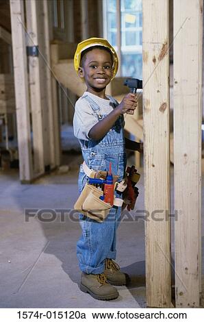 Stock Image - Portrait of a boy dressed as a construction worker holding a toy hammer. Fotosearch