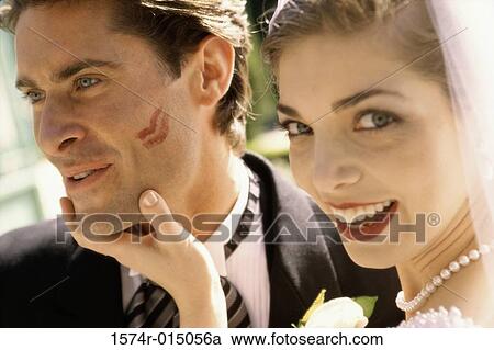 Stock Image - Portrait of a bride holding her groom's face. Fotosearch