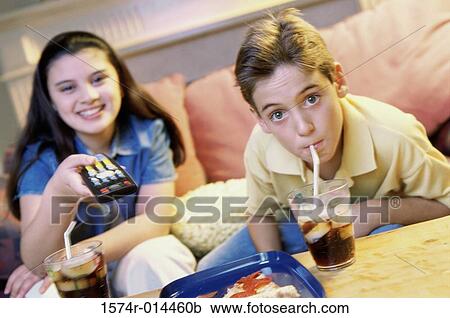 Stock Image - Portrait of a brother and sister watching television. Fotosearch