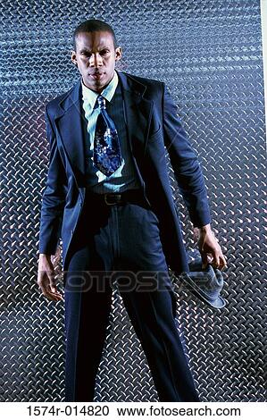 Stock Image - Portrait of a businessman standing in front of a metallic wall. Fotosearch