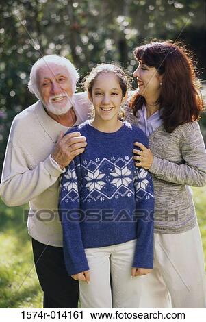 Stock Image - Portrait of a daughter standing with her mother and grandfather smiling. Fotosearch