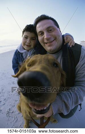 Stock Image - Portrait of a father and son with their dog. Fotosearch