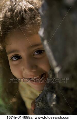 Portrait of a girl hiding behind a rock View Large Photo Image Stock Image - Portrait of a girl hiding behind a rock. Fotosearch