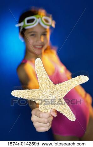 Stock Image - Portrait of a girl holding a starfish. Fotosearch