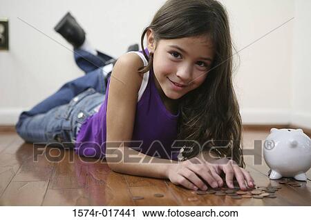 Portrait of a girl lying on the floor with a piggy bank beside her View Large Photo Image Stock Image - Portrait of a girl lying on the floor with a piggy bank beside her. Fotosearch