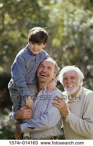 Stock Image - Portrait of a grandfather smiling with his son and grandson in a park. Fotosearch