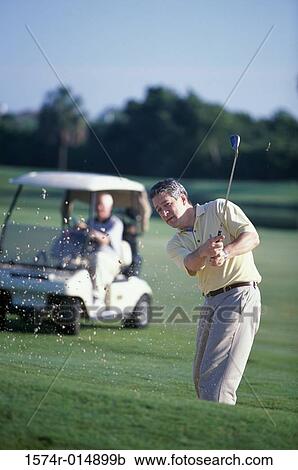 Stock Image - Portrait of a mature man swinging a golf club. Fotosearch