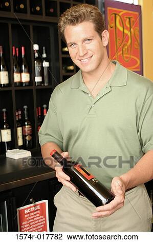 Portrait of a mid adult man holding a wine bottle in a liquor store View Large Photo Image Stock Image - Portrait of a mid adult man holding a wine bottle in a liquor store. Fotosearch