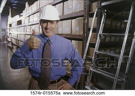 Portrait of a mid adult man making a thumbs up sign in a warehouse View Large Photo Image Stock Image - Portrait of a mid adult man making a thumbs up sign in a warehouse. Fotosearch