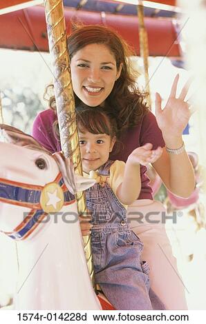 Stock Image - Portrait of a mother and her daughter sitting on a carousel horse. Fotosearch