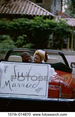 Stock Image - Portrait of a newlywed couple sitting in a car. Fotosearch