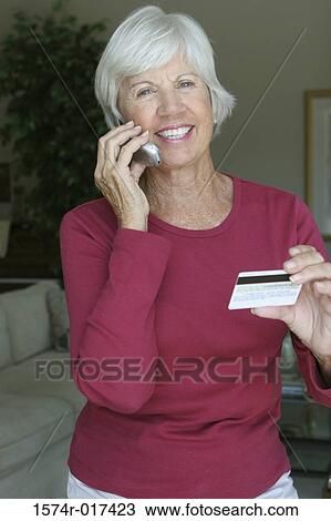 Portrait of a senior woman talking on a mobile phone holding a credit card View Large Photo Image Stock Image - Portrait of a senior woman talking on a mobile phone holding a credit card. Fotosearch