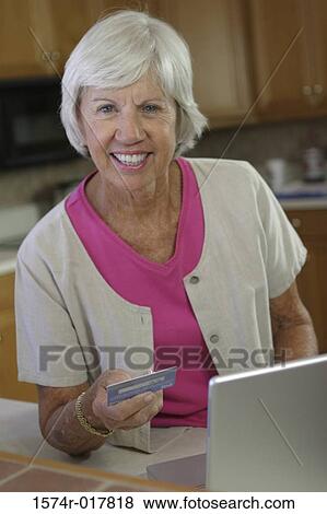 Stock Photo - Portrait of a senior woman using a laptop holding a credit card. Fotosearch