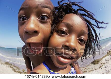 Stock Image - Portrait of a sister smiling with her brother standing behind her. Fotosearch
