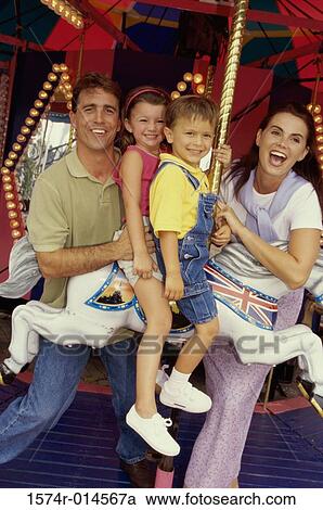 Portrait of a son and daughter sitting on a carousel horse with their parents standing beside them View Large Photo Image Stock Image - Portrait of a son and daughter sitting on a carousel horse with their parents standing beside them. Fotosearch