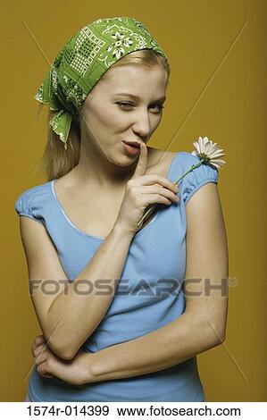 Stock Photo - Portrait of a teenage girl holding a flower with a finger on her lips. Fotosearch