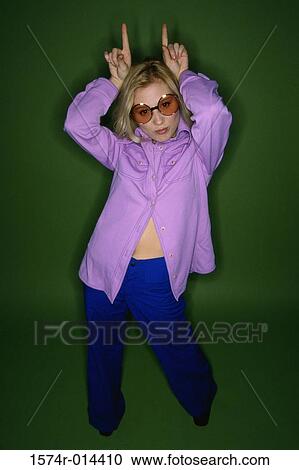 Stock Image - Portrait of a teenage girl making a horn sign. Fotosearch