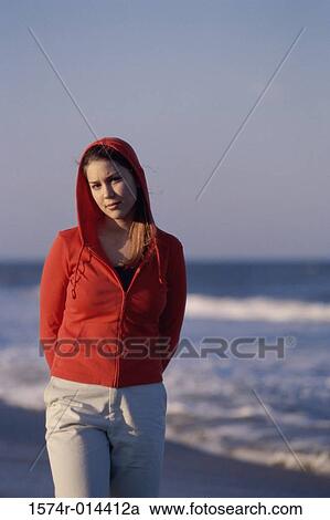 Stock Image - Portrait of a teenage girl wearing a hooded shirt on the beach. Fotosearch