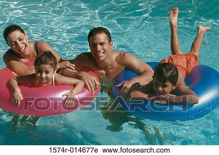 Stock Image - Portrait of a young couple in a swimming pool with their son and daughter. Fotosearch