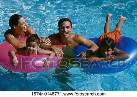 Stock Image - Portrait of a young couple in a swimming pool with their son and daughter. Fotosearch