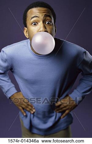 Stock Image - Portrait of a young man blowing a bubble. Fotosearch