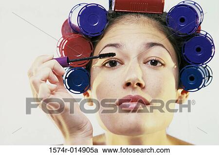 Stock Image - Portrait of a young woman applying mascara. Fotosearch