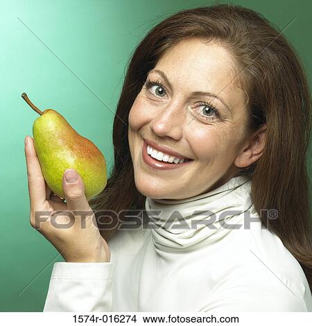 Portrait of a young woman holding a pear View Large Photo Image Picture - Portrait of a young woman holding a pear. Fotosearch
