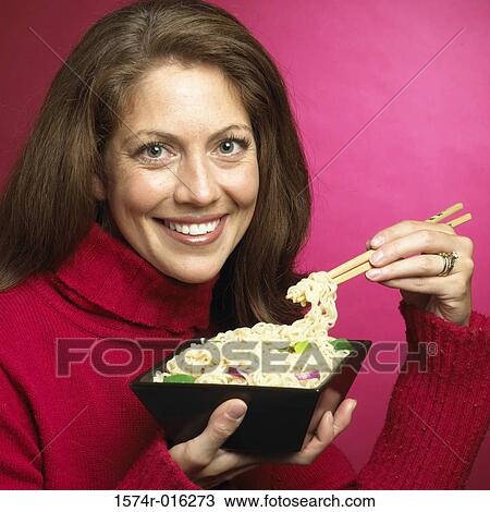 Portrait of a young woman holding noodles with chopsticks View Large Photo Image Stock Image - Portrait of a young woman holding noodles with chopsticks. Fotosearch