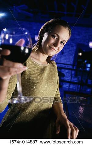 Stock Photo - Portrait of a young woman offering a glass of red wine. Fotosearch