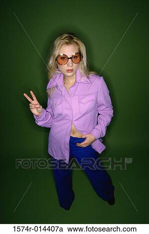 Stock Image - Portrait of a young woman showing a peace sign. Fotosearch