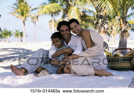Stock Image - Portrait of parents and their daughter sitting on the beach. Fotosearch
