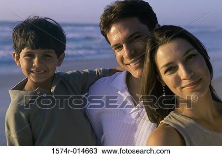 Stock Image - Portrait of parents and their son smiling on the beach. Fotosearch