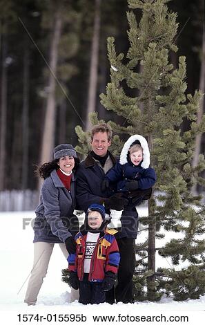 Stock Image - Portrait of parents with their son and daughter standing in snow. Fotosearch