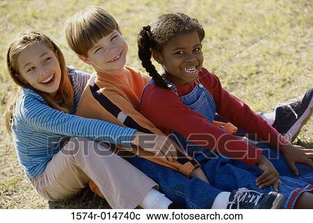 Portrait of two girls and a boy sitting on a lawn View Large Photo Image Stock Image - Portrait of two girls and a boy sitting on a lawn. Fotosearch