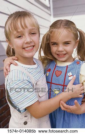Stock Image - Portrait of two girls hugging each other. Fotosearch