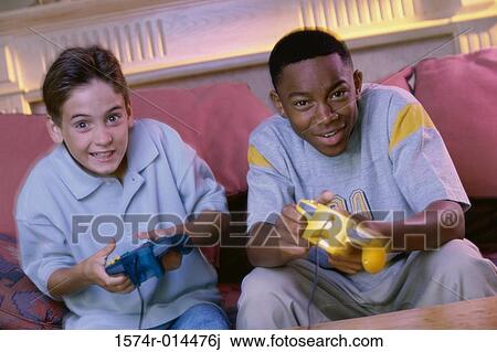Stock Image - Portrait of two teenage boys playing video games. Fotosearch