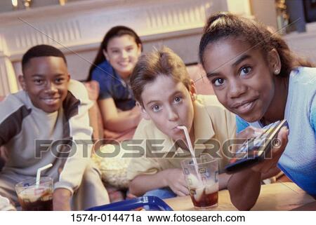 Stock Image - Portrait of two teenage girls and two teenage boys watching television together. Fotosearch