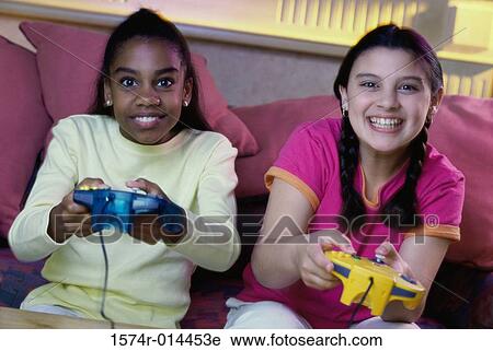 Stock Image - Portrait of two teenage girls playing video games. Fotosearch