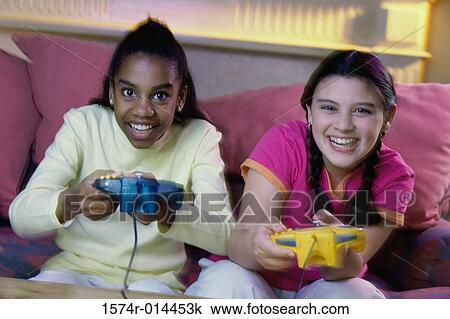 Stock Image - Portrait of two teenage girls playing video games. Fotosearch