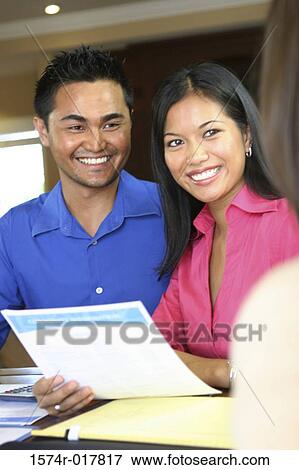Stock Photo - Real estate agent talking to a young couple. Fotosearch